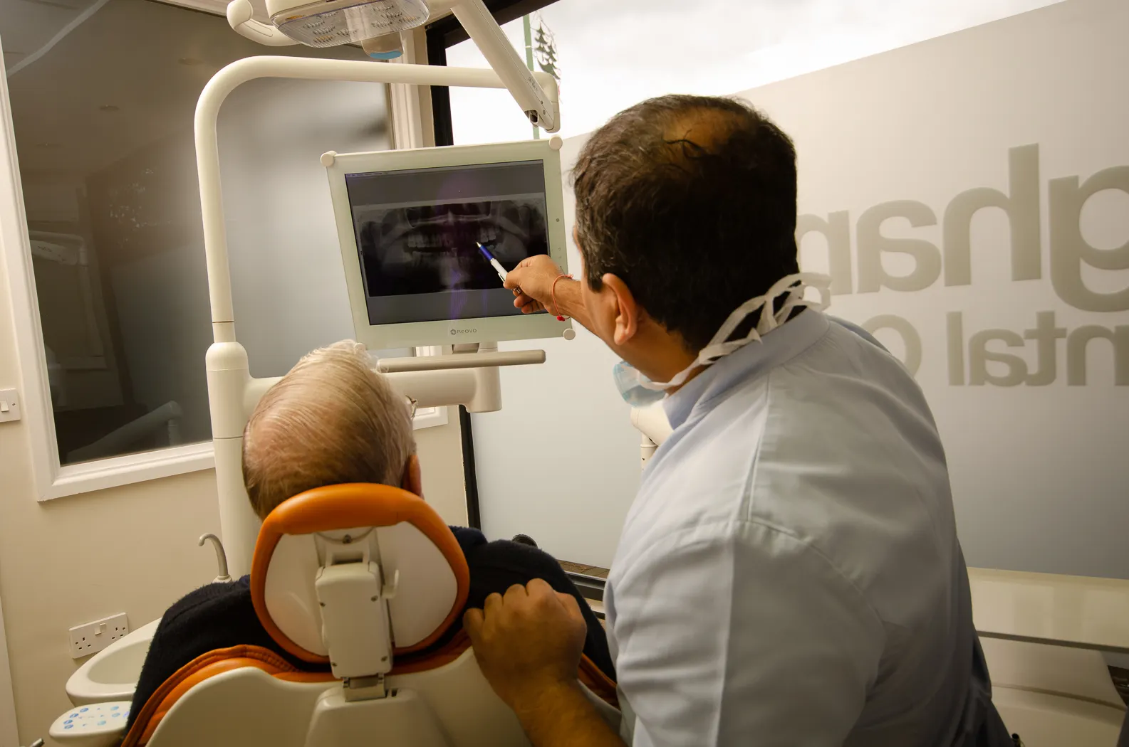 Dentist explaining dental X-ray results to an elderly male patient in clinic.